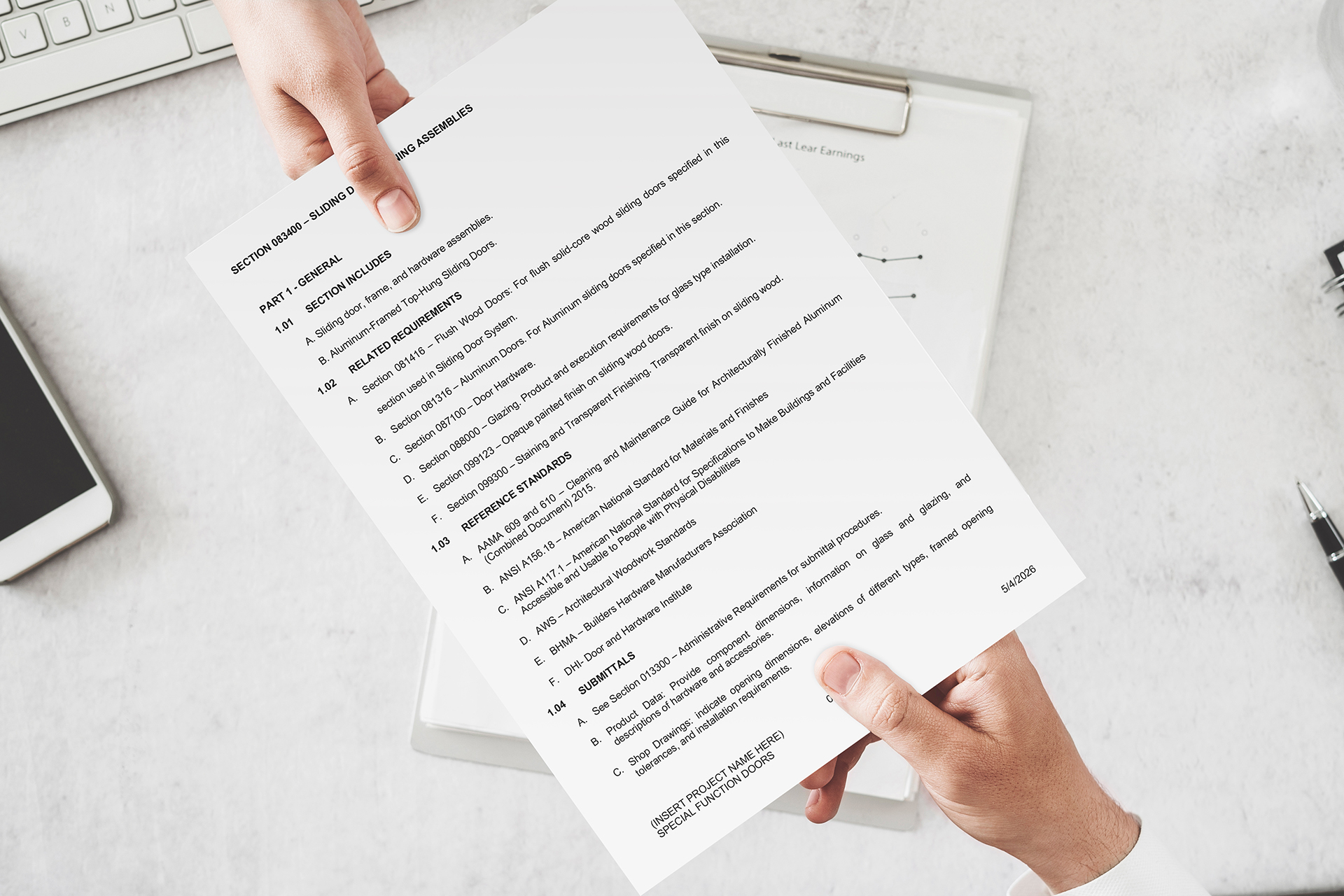 Person’s hands hold a printed document with dense text over a light desk with a keyboard nearby, like a contract or spec sheet.